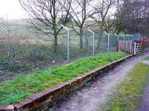 Chain link fence on galvanised steel posts with cranked arm tops supporting 3no. strands of barbed wire