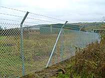 Heavy duty galvanised chain link fence on galvanised steel  fence posts with cranked arm tops supporting 3no. strands of barbed wire