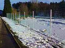 Chain link mesh on galvanised steel posts vertically extended with 4no. strands of barbed wire