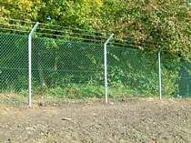 Chain link fence on galvanised steel posts with cranked arm tops supporting 3no. strands of barbed wire