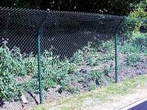 Chain link fencing supported on steel fence posts - posts have a top cranked arm to allow the chain link to be curved over at the top - This particular fence was located next to a model car race track to act as a catch fence