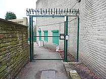 Green powder coated mesh in-filled access gate with key pad access - gate secured with a magnetic lock - top of gate protected by a single row of rotating spikes