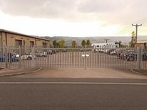 Galvanised palisade entrance gates with padlock cover hoods - gate entrance includes an additional pedestrian access gate to separate pedestrians from vehicular road traffic