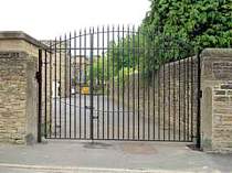 Double leaf vertical bar entrance gates incorporating a bowed top