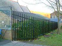 Black powder coated palisade fencing with a raked fence panel