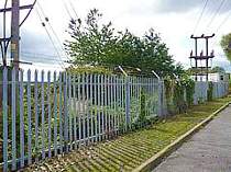 Cranked arm angle steel barbed wire extensions bolted to the existing steel palisade fencing