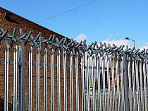 350mm galvanised rotating spikes fixed to the top of a palisade fence - support brackets cranked inwards towards the property to make sure the rotating spikes do not extend into the public pavement